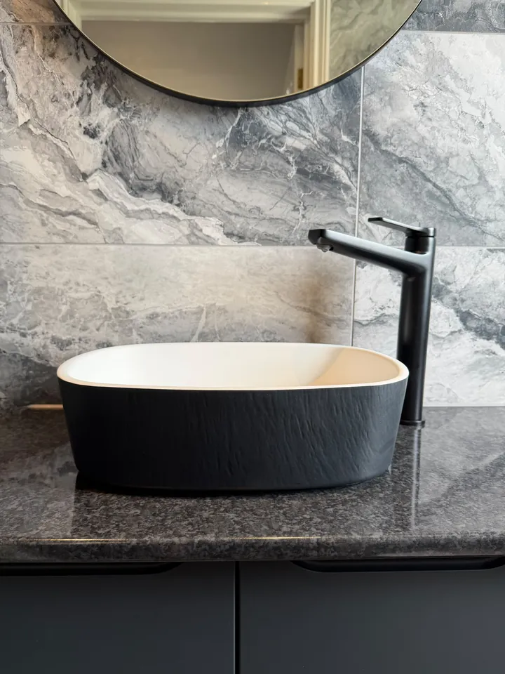 Black countertop basin and matte black tap on a dark stone worktop