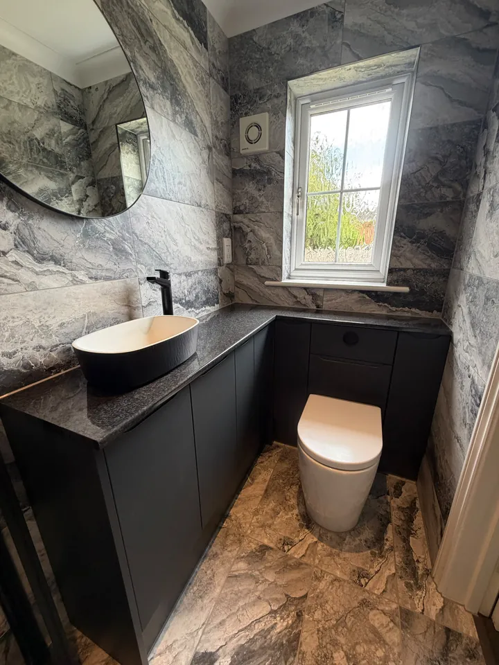 Cloakroom with marble-effect walls, black vanity and countertop basin