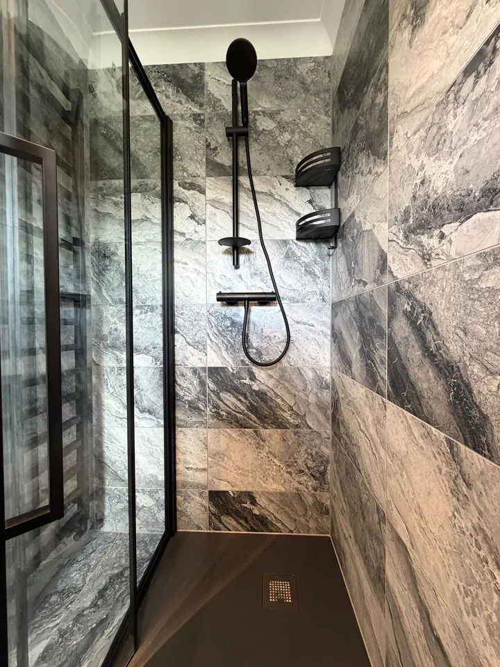 Walk-in shower with marble-effect tiling and matte black fittings